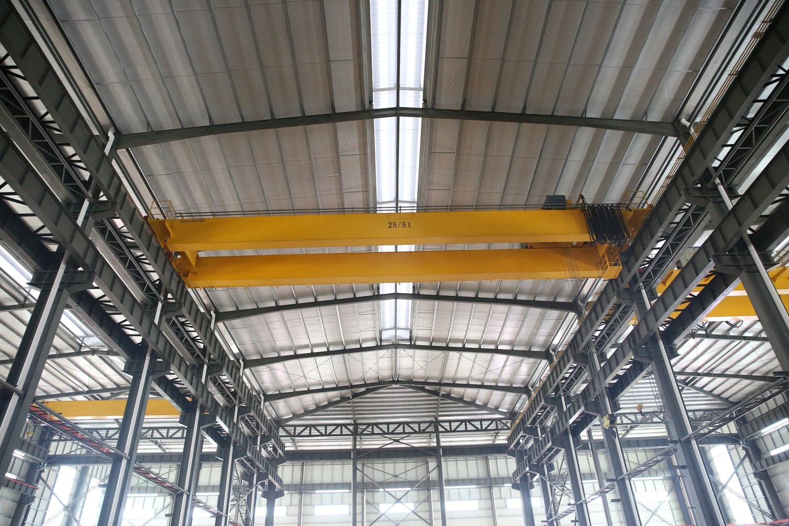 Yellow overhead crane installed in a mining equipment manufacturing workshop